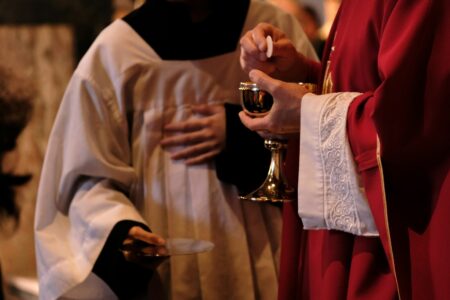 A priest is holding a glass of wine