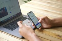 Person using smartphone and credit card with laptop